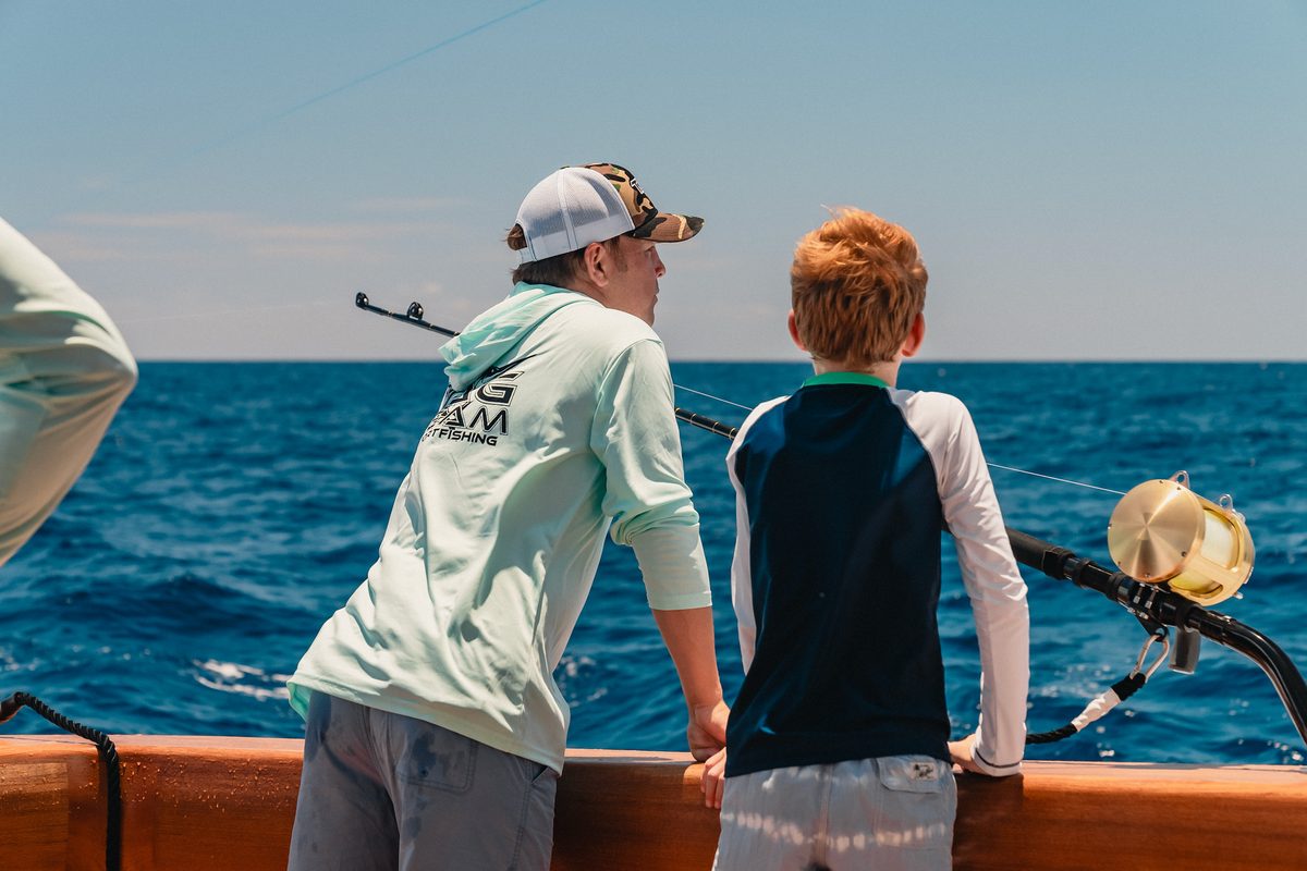 Two anglers at the rail of a charter boat watching their lines on open water